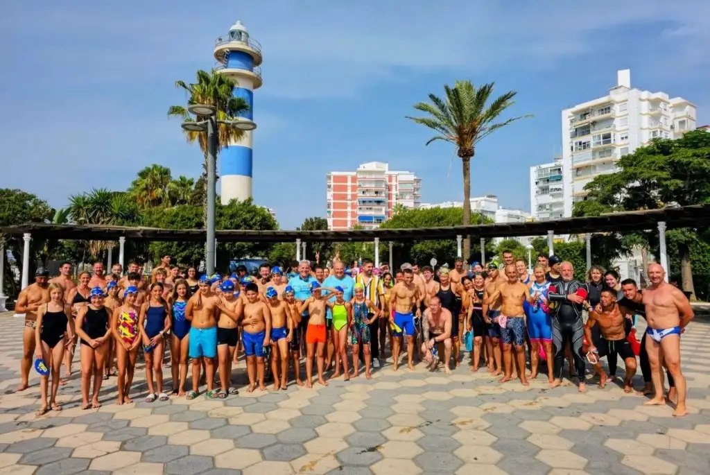 Nadadores y familias junto al faro de Torre del Mar, en la Travesía Pepe Fajardo del club